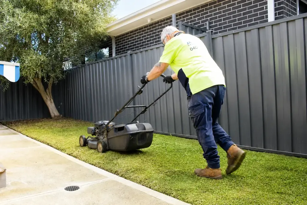 James mowing a backyard lawn beside a Colorbond fence in Werribee