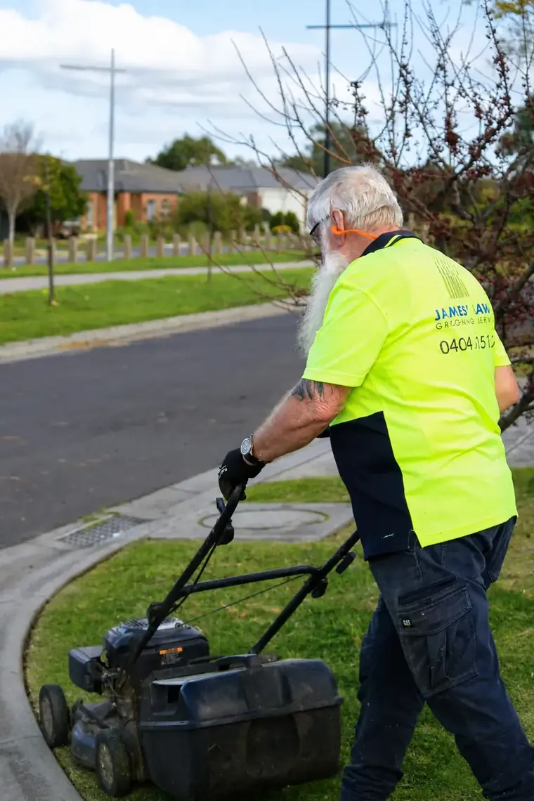 James pushing the mower along a nature strip in Hoppers Crossing